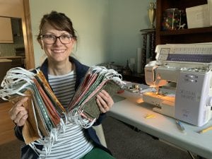 Cincinnati Parks volunteer holding up all of the masks she made for parks staff