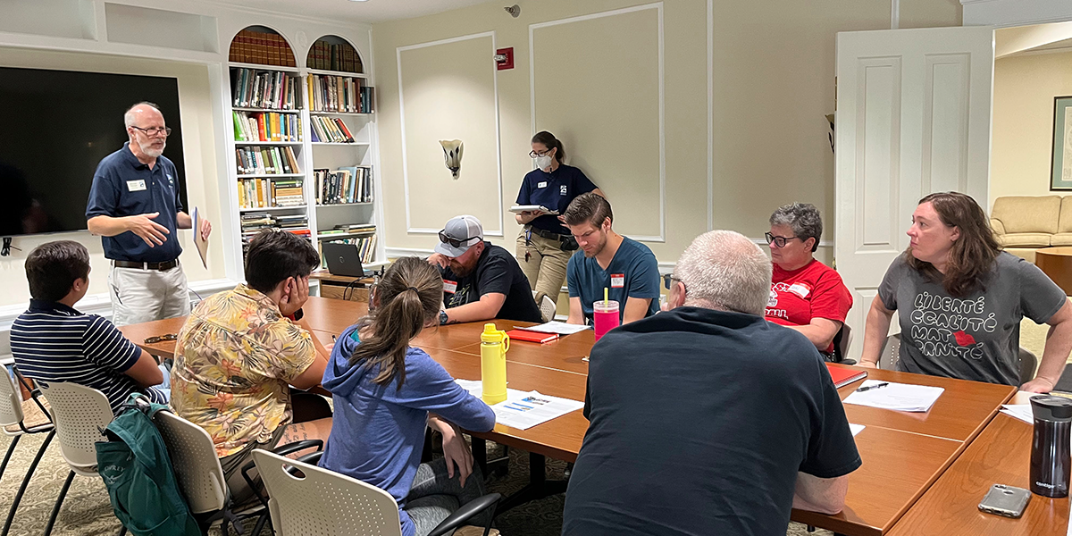 Group of volunteers in training at a table listening to Naturalist speak